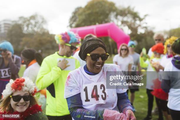 laughing female runner covered in holi powder at charity run in park - paint race stock pictures, royalty-free photos & images