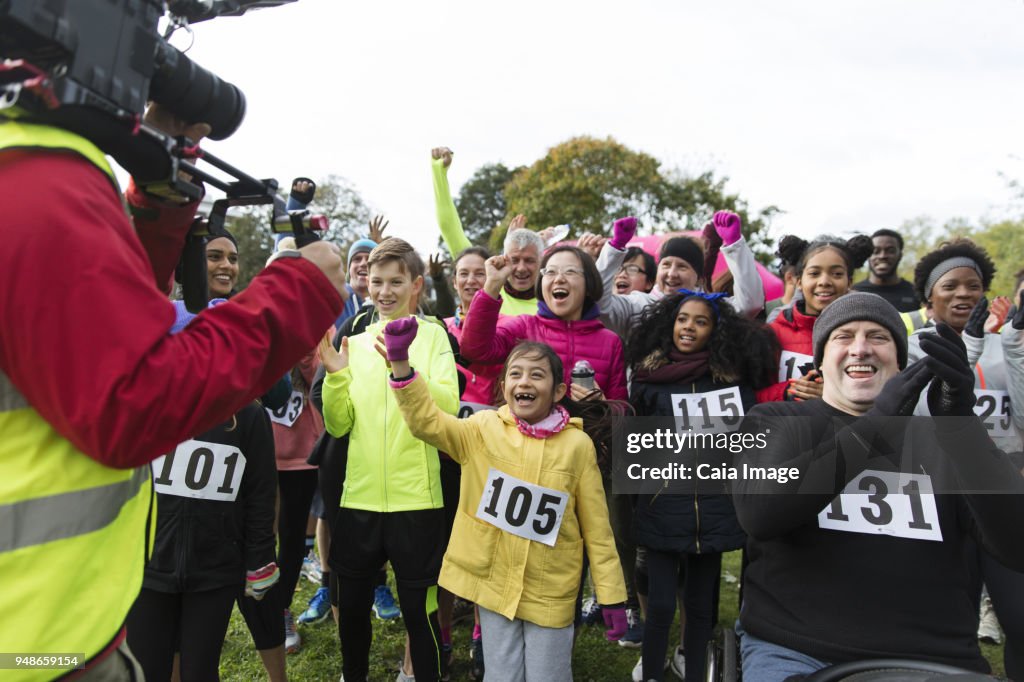 Cameraman filming cheering crowd of runners at charity race