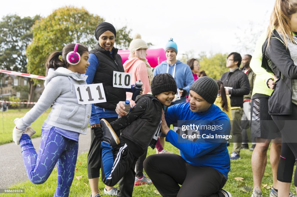Family runners preparing, stretching at charity run in park