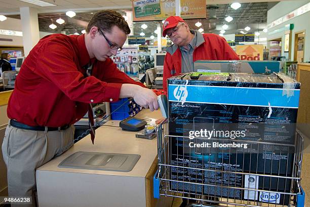 Employee Dustin Coffman, left, scans a Hewlett Packard computer being purchased by John Hancock, right, inside a Micro Center store Columbus, Ohio,...