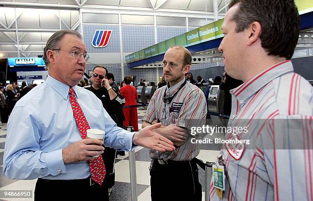 Glenn Tilton, United Airlines president and chief executive officer, left, gestures to employees Jim Davis, center, and John Nedbal in Terminal One...