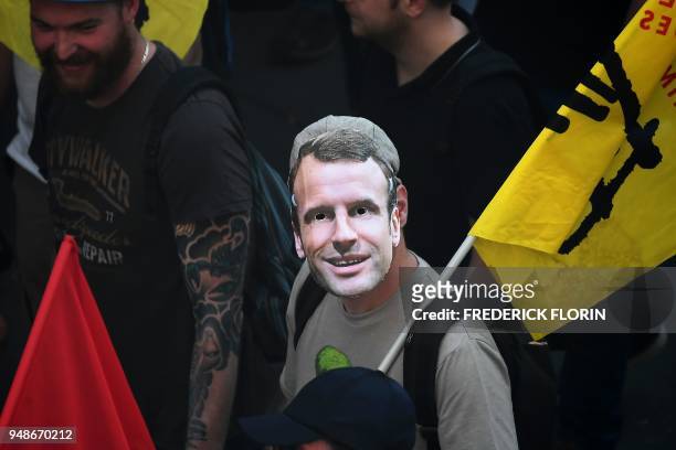 Man wearing a mask of French President Emmanuel Macron attends a demonstration on April 19, 2018 in Strasbourg, eastern France as part of a multi...
