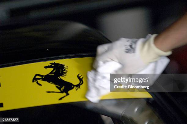 Worker polishes the logo on a Ferrari car prior to an auction of Ferrari amd Maserati cars by Sotheby's in Maranello, Italy, Tuesday, June 21, 2005.