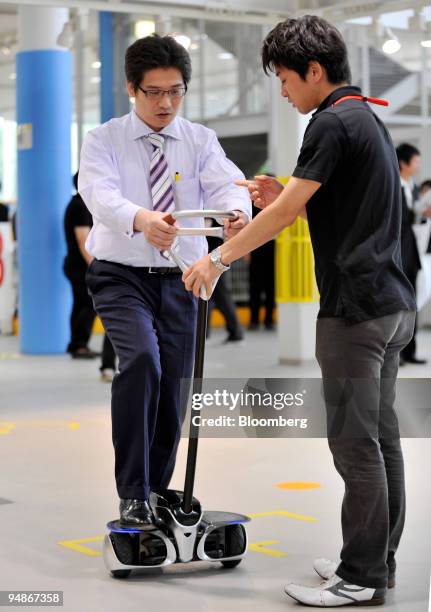 Journalist is assisted by a staff member during ride on Toyota Motor Corp.'s newly developed personal transport assistance robot "Winglet" type L in...