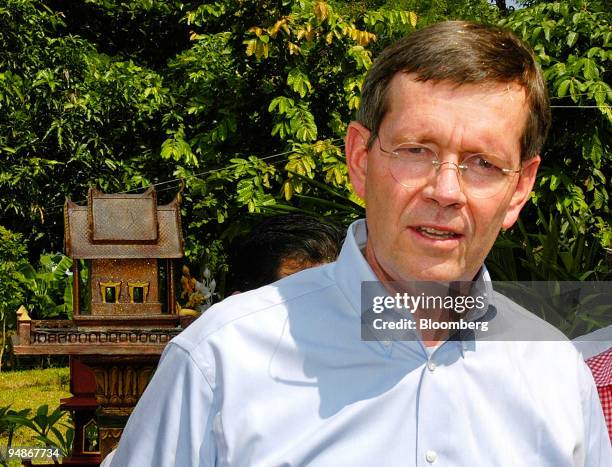 Visiting U.S. Health and Human Services Secretary Michael O. Leavitt talks to reporters near a 'Thai spirit house,' left, on a small chicken farm...
