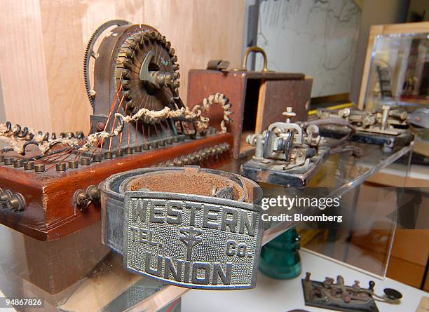 Western Union belt and buckle pictured in front of antique sending and receiving gear at the First Data Corp. Archive in Greenwood Village, Colorado...