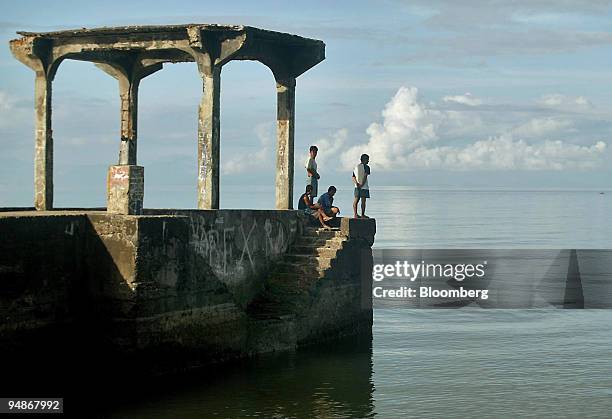 Filipinos hang out at the end of an abandoned pier on an empty beach near the Boac River's termination into the Sibuyan Sea on Marinduque Island in...