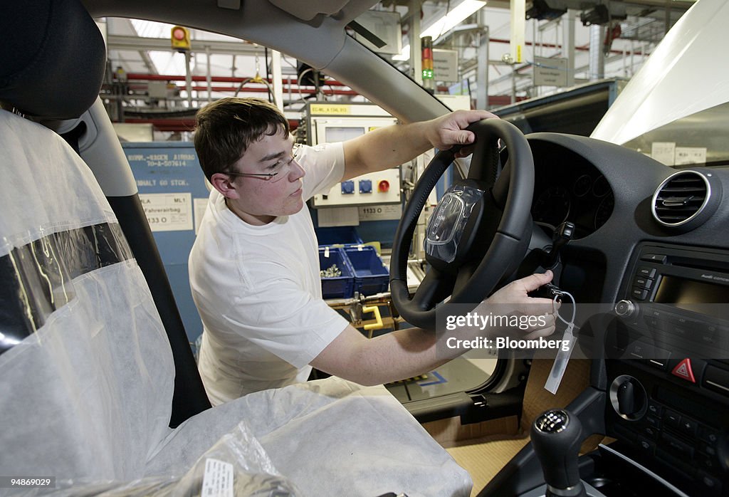 A worker installs a steering wheel in an automobile at the A