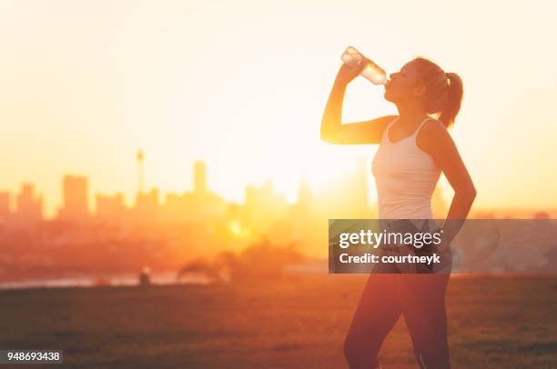 silhouette einer frau trinken bilden eine kalte flasche wasser. - bottle water sport stock-fotos und bilder