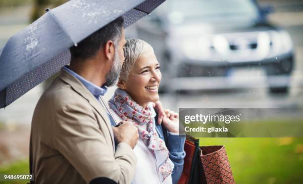 passeggiata piovosa a casa dallo shopping. - outdoor umbrella foto e immagini stock