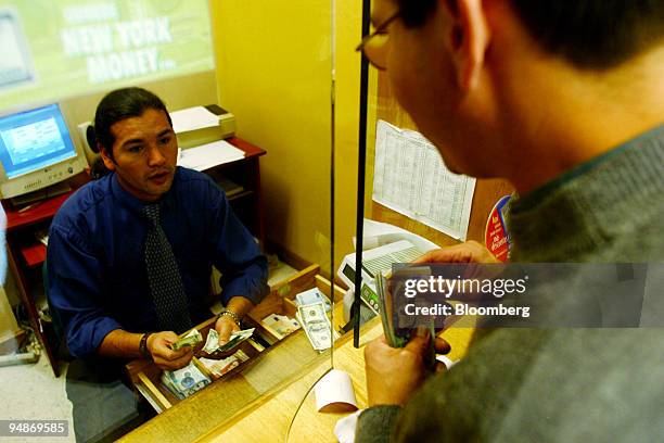 Money changer exchanges Colombian peso's for U.S. Dollars for a customer at a foreign exchange in Bogota on Monday, February 23, 2004. Colombia's...