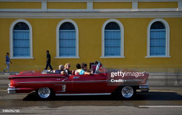 People ride an old American car through the streets of Havana on April 19 day in which Miguel Diaz-Canel was formally named Cuba's new president, and...