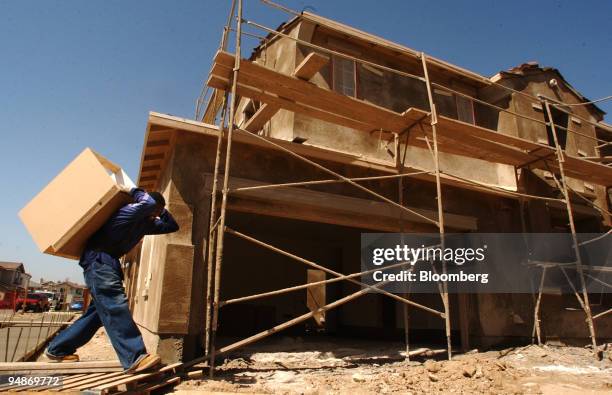 Taylor Jones carries a kitchen cabinet into a home under construction in the East Lake section of Chula Vista, California, March 16, 2004. U.S....