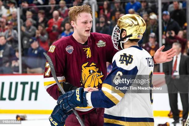 Riley Tufte of the Minnesota-Duluth Bulldogs shakes hands with Tory Dello of the Notre Dame Fighting Irish following the Division I Men's Ice Hockey...