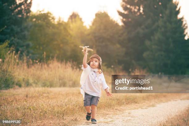 kleiner junge spielt mit hölzernen flugzeug im park - toy airplane stock-fotos und bilder