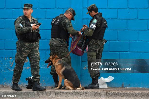 Military police officers search students' backpacks at the entrance of a school in Tegucigalpa, on April 18, 2018. - Students are also victims of the...