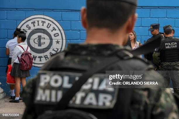 Student caught with marijuana waits against a wall as military police officers search other students' backpacks at the entrance of the Vicente...