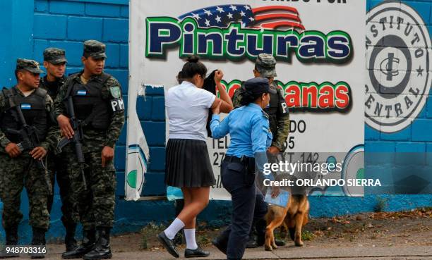 Military police officers observe a policewoman escorting a student who was caught with marijuana on her backpack, as they stand guard outside the...