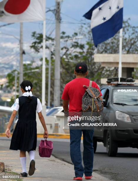 Man walks her daughter to school in Tegucigalpa, on April 18, 2018. - Students are also victims of the prevailing insecurity in Honduras, where the...