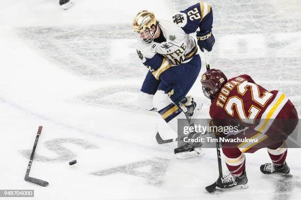 Andrew Peeke of the Notre Dame Fighting Irish and Jared Thomas of the Minnesota-Duluth Bulldogs chase a loose puck during the Division I Men's Ice...