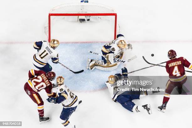 Jordan Gross of the Notre Dame Fighting Irish clears a shot attempt by Dylan Samberg of the Minnesota-Duluth Bulldogs during the Division I Men's Ice...