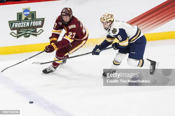 Riley Tufte of the Minnesota-Duluth Bulldogs and Jake Evans of the Notre Dame Fighting Irish chase a loose puck during the Division I Men's Ice...