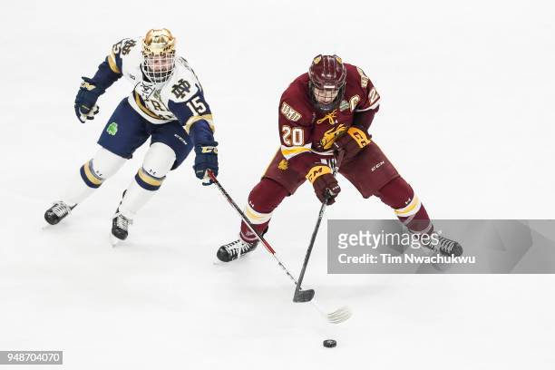 Andrew Oglevie of the Notre Dame Fighting Irish tries to dispossess Karson Kuhlman of the Minnesota-Duluth Bulldogs during the Division I Men's Ice...