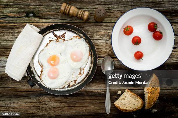 pan of fried eggs and cherry-tomatoes with homemade bread - crepe textile stock-fotos und bilder