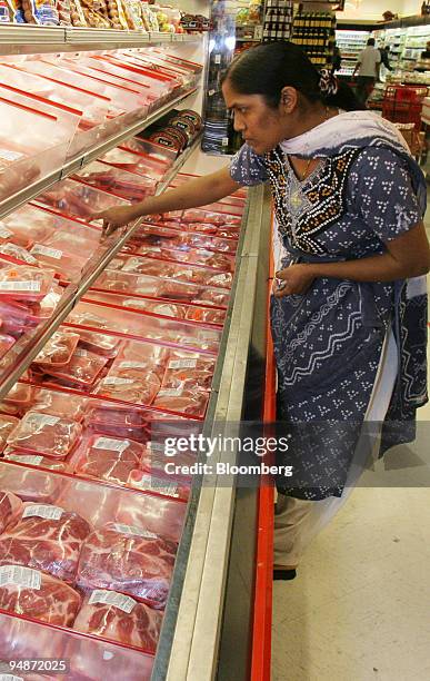 Felcy Vagas looks over pork products in the meat case of an Associated Supermarket in New York, Wednesday, June 15, 2005. Prices paid by U.S....