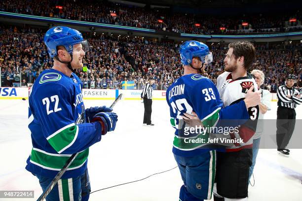 Daniel Sedin looks on as Henrik Sedin of the Vancouver Canucks is hugged by Oliver Ekman-Larsson of the Arizona Coyotes after their NHL game at...