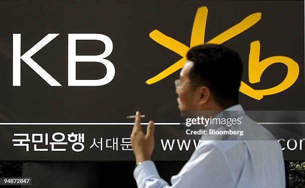 An office worker takes a break in front of a Kookmin Bank street advertising board in Seoul, South Korea Friday, October 22, 2004. Kookmin Bank,...