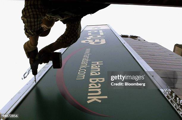 An advertising agency worker sets up Hana Bank's standing signboard in front of an office in Seoul, South Korea Friday, October 22, 2004. Hana...