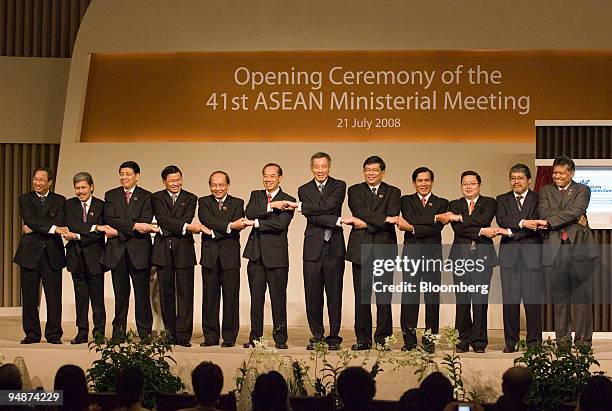 Ministers attending the 41st Association of Southeast Asian Nations Ministerial Meeting link arms during the opening ceremony, in Singapore, on...