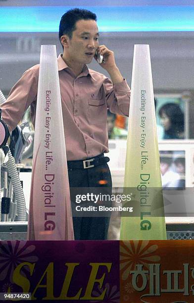 Sales clerk waits for customers as he talks on cellular phone at the LG Digital Plaza in Ilsan, South Korea Monday, October 18, 2004. South Korea's...