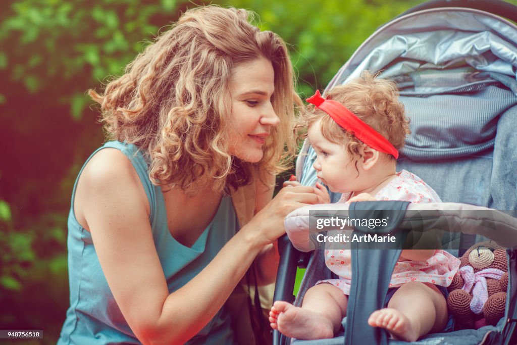 Mother and her baby daughter in stroller in park