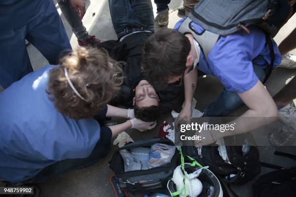 An injured young man receives first aid after being hit on the head by anti-riot police during clashes on the sidelines of a demonstration on April...