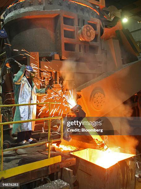 Worker Rick Tyo uses an oxygen lance to clear slag and impurities out of a pipe that feeds liquid steel into a mold to cast a continuous slab at...