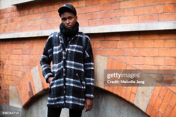 Model Shalisha Stewart wears a black leather cap, black scarf, and black and white tartan jacket during London Fashion Week February 2018 on February...