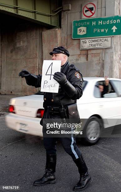 Motorcycle police officer holds a sign up as he allows only vehicles carrying four or more people onto the West Side Highway in New York Tuesday,...
