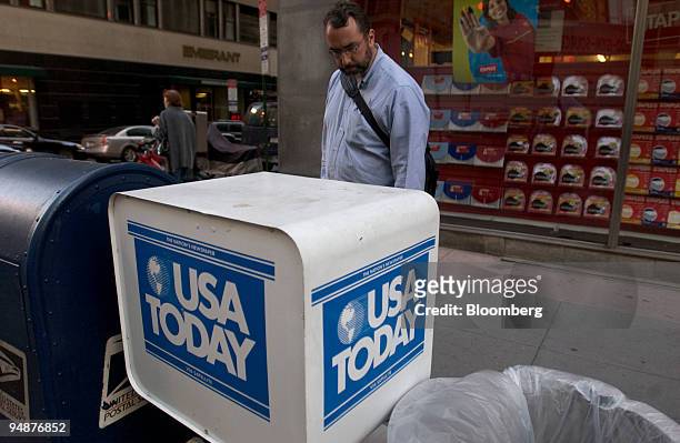Man looks over the front page of a USA Today newspaper on display in an honor box in New York on October 12, 2004. Gannett Co., the largest U.S....