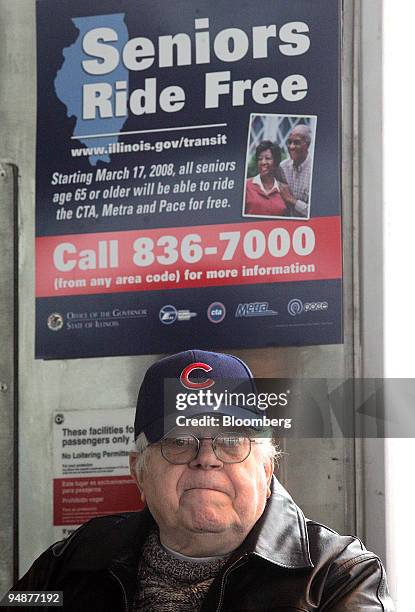 Wearing his Chicago Cubs baseball hat, Leonard Rink sits under a sign promoting free rides for seniors in a Chicago Transit Authority transit station...