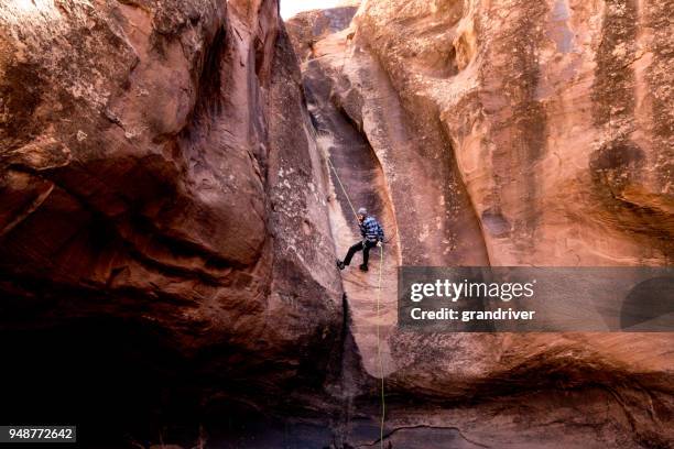 athletic young man rappelling near moab utah - canyoneering stock pictures, royalty-free photos & images