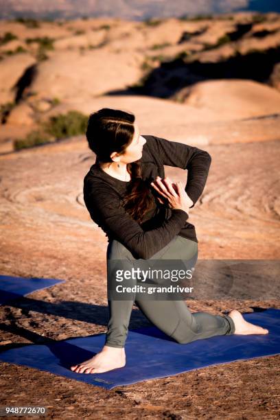 woman performing twisting yoga pose at dusk in moab - spinal twist stock pictures, royalty-free photos & images