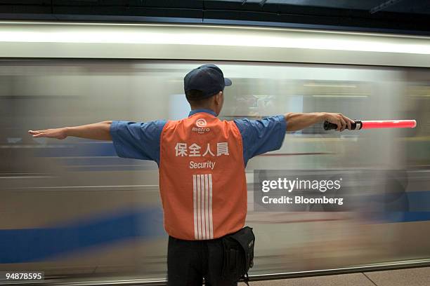 Security guard keeps passengers at a safe distance from an arriving mass-transit train in Taipei's Zhongxiao Fuxing MRT subway station Wednesday,...