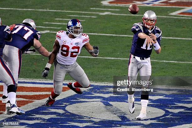 Tom Brady of the New England Patriots, right, throws a pass under pressure from the Michael Strahan of the New York Giants during the first half of...
