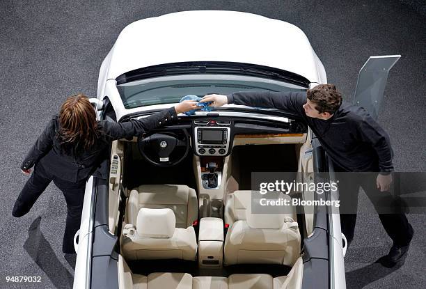 Volkswagen employees Katja Schoenfelder, left, and Werner Marcus clean a Volkswagen Eos car at the company's annual earnings news conference in...