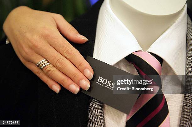 Woman adjusts the Hugo Boss label on a suit in a store in Cologne, Germany, Saturday, October 29, 2005. The company's earnings are scheduled to be...