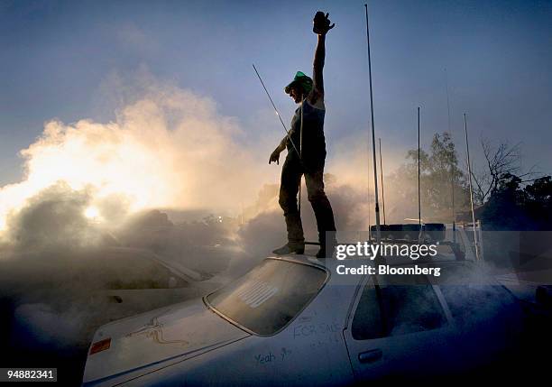 Reveler attending the Bachelor and Spinsters ball stands atop a car, in Trundle, Australia, on Saturday, March 1, 2008. With 48 cans of beer in the...