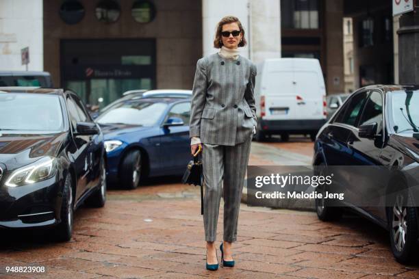 Model Giedre Dukauskaite wears a matching gray double-button plaid suit over a tan turtleneck, with blue heels and a black purse during Milan Fashion...