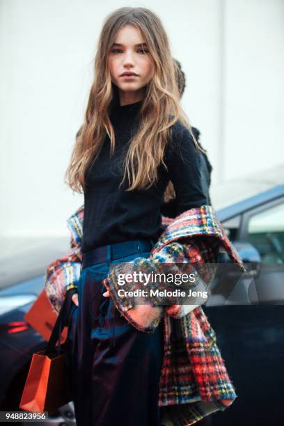 Model Meghan Roche wears a black top and pants with a red plaid coat around her waist after the Missoni show during Milan Fashion Week Fall/Winter...